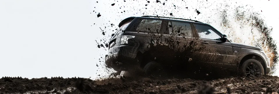 Powerful SUV driving on a muddy road, kicking up debris