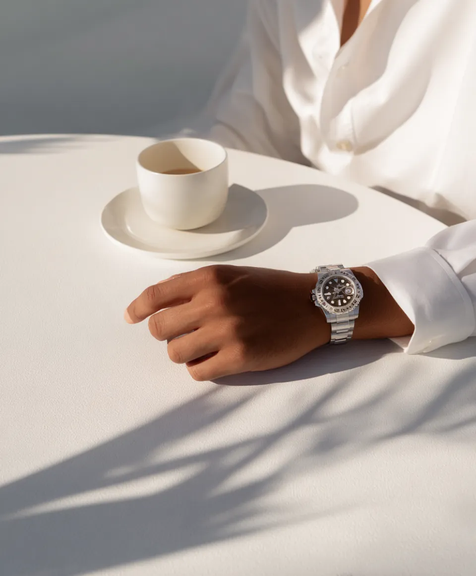 Elegant hand with a watch and a cup on a white table