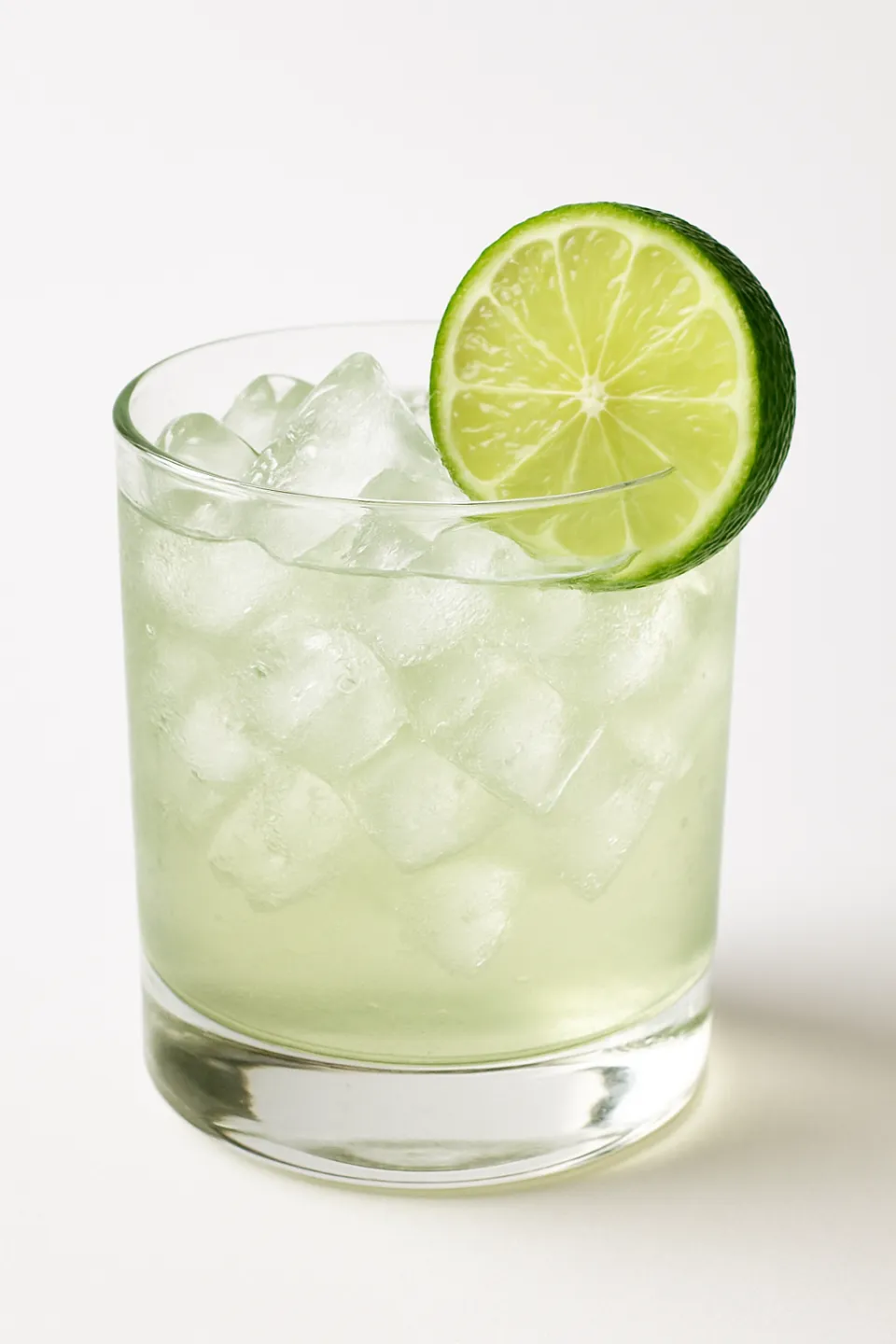 Cocktail with ice cubes and a slice of lime on the edge of the glass