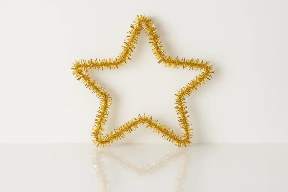 Золотая звезда, созданная из блестящей мишуры, на светлом фоне