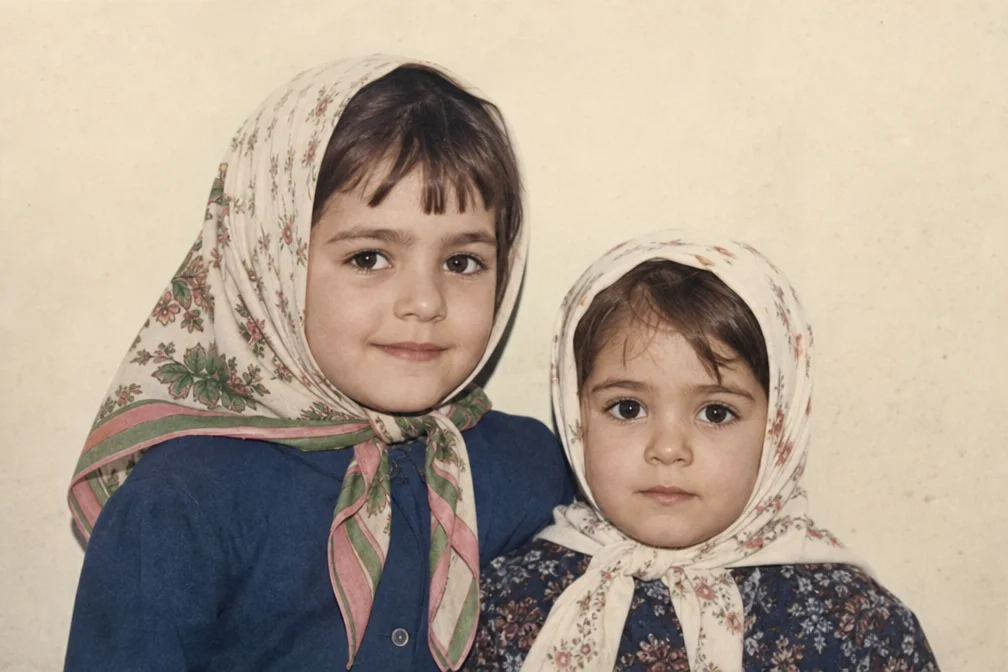 Restore an old, damaged photograph of two young children wearing headscarves. T…