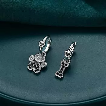 Ювелирные серьги-подвески с черными и белыми камнями в виде лап и костей