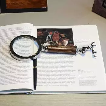 Лупа с серебряной головой оленя в металлическом каркасе. Практичный инструмент.
