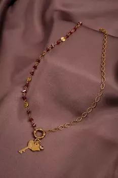 Ожерелье золотого цвета с красным хрустальным камнем