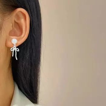 Простые серьги-подвески с бантом из жемчуга. Модные серьги-подвески. Девочки носят ювелирные украшения в качестве подарков на дни рождения.