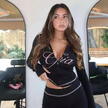 Узкие плечи с монограммой и ярким нитевым принтом, узкая короткая куртка с капюшоном и молнией, брючный костюм S