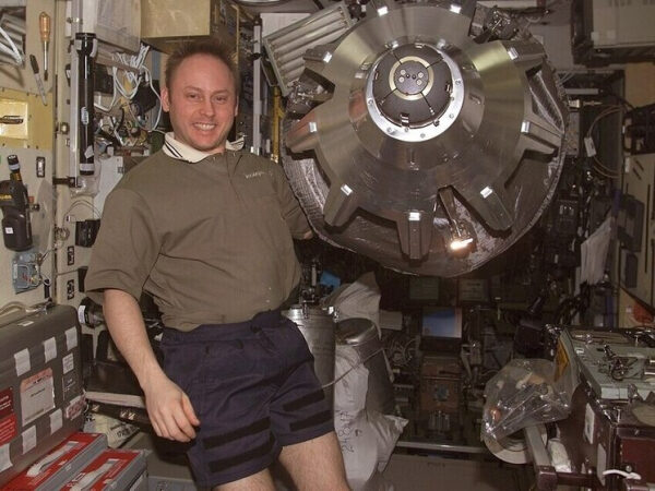 Астронавт в космическом модуле рядом с крупным металлическим устройством.