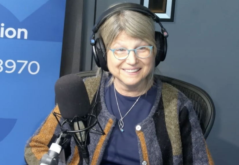 Человек в наушниках говорит в микрофон в радиостудии, синий задний фон.