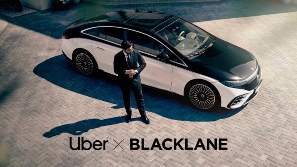 Мужчина в костюме у роскошного черно-белого автомобиля, логотипы Uber и Blacklane.