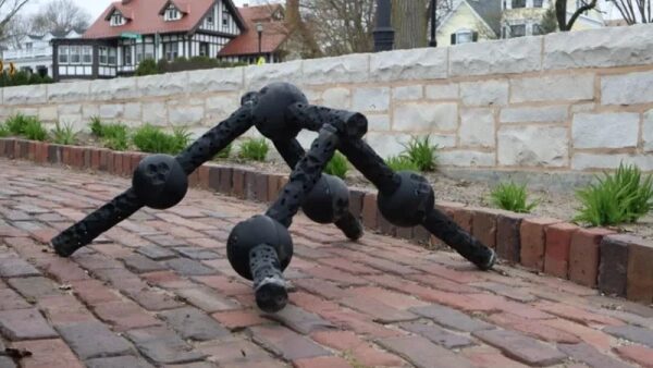 Металлическая арт-инсталляция в форме паука на кирпичной дорожке.