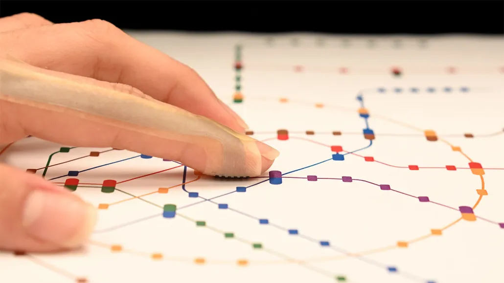 Это устройство, похожее на пластырь, позволит вам "почувствовать" виртуальный мир 2 Пальцы на тактильной карте метро с цветными маршрутами.