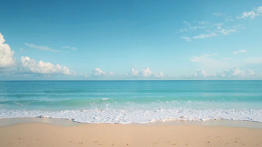 Экспериментируйте: постройте свой собственный пляж! 6 Песчаный пляж и спокойное голубое море с облачным небом на горизонте.