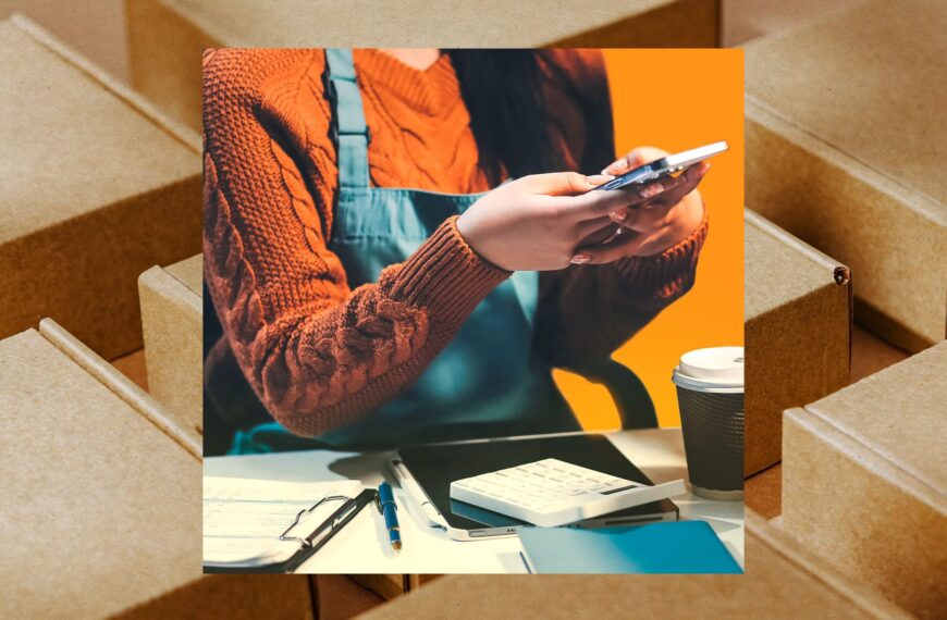 Женщина в свитере с телефоном, стол с калькулятором и бумагами, кофейный стакан.