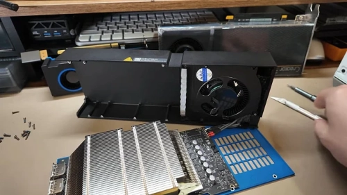 Разобранная видеокарта с системой охлаждения и радиатором на столе.