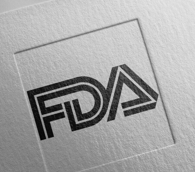 Логотип FDA на текстурированной бумаге, черно-белый дизайн с объемными буквами.