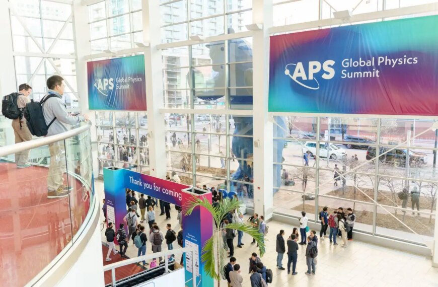 Конференция Global Physics Summit, люди в холле, баннер APS, большое остекление.