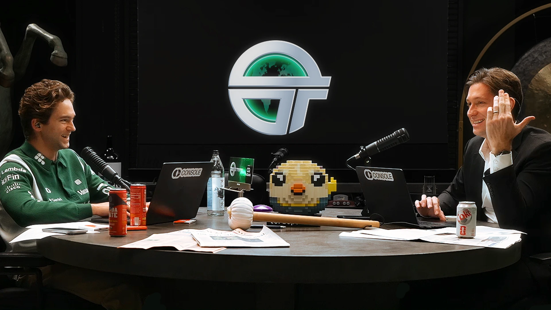 OpenAI приобретает TBPN | OpenAI 4 Двое мужчин за столом с ноутбуками и микрофонами, фон с логотипом.