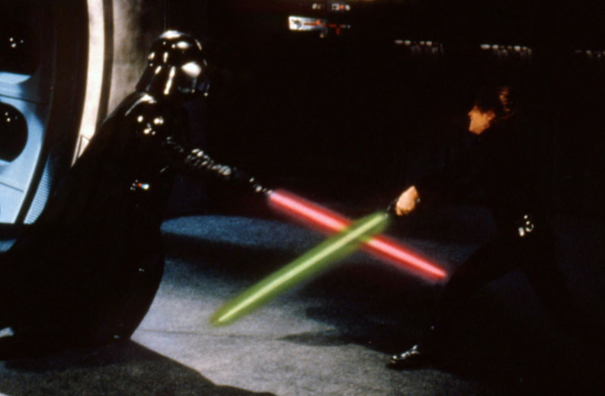 Два персонажа сражаются световыми мечами на темном фоне сцены из фильма.