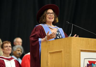 Человек в академической мантии выступает на церемонии вручения дипломов.