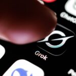 Палец нажимает на иконку приложения Grok на экране смартфона.
