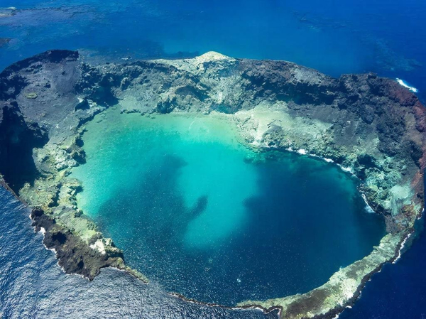 Вулканический кратер с бирюзовой водой, вид с высоты в океане.