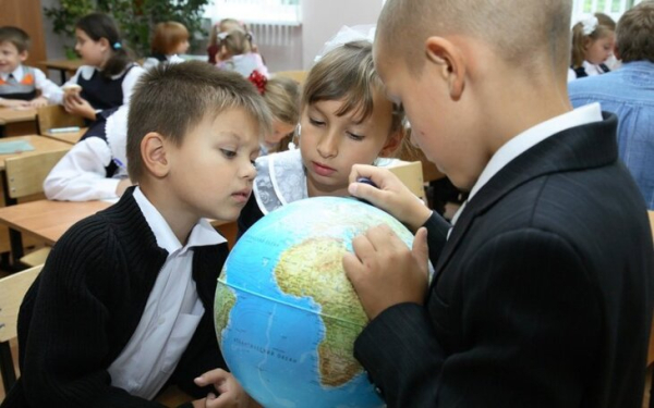 Дети изучают глобус в классе, школьный урок географии.