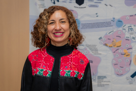 Человек в красной куртке с цветочным узором на фоне карты.