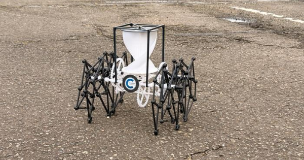 Шестиногий робот на асфальте, напоминающий паука, черно-белый дизайн, механизмы и трубки.