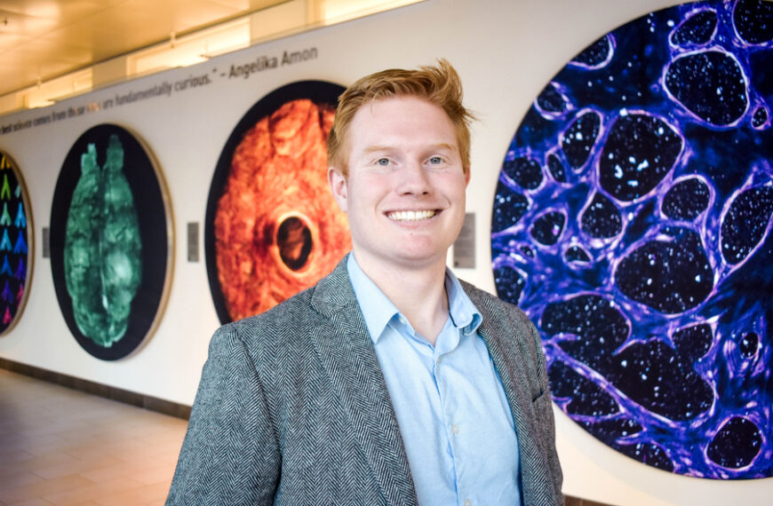 Мужчина в галерее с крупными яркими абстрактными картинами на стене.