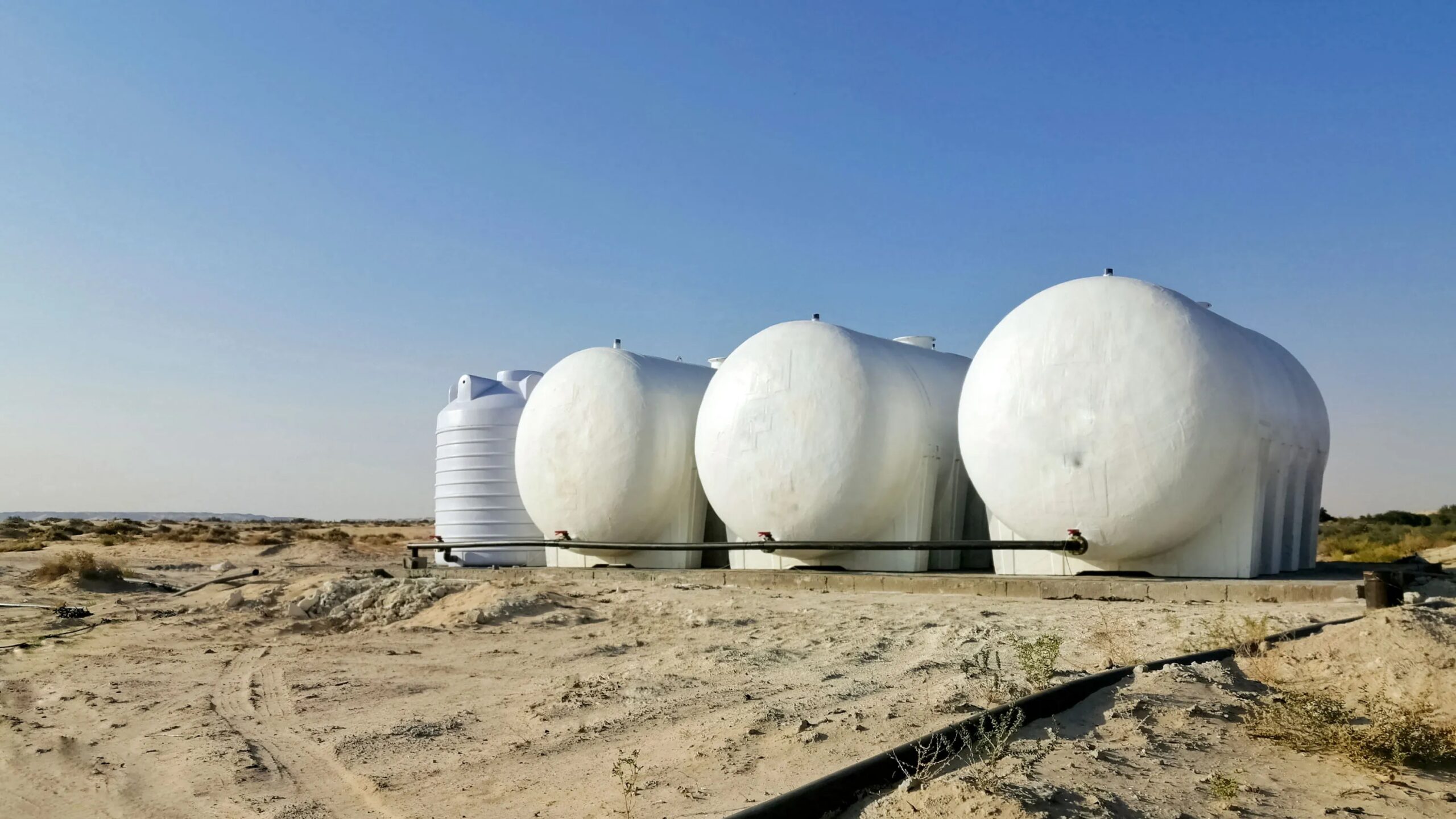 Белые резервуары для хранения воды на фоне пустынного пейзажа.
