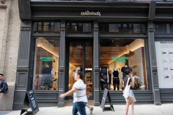Фасад магазина обуви Allbirds с прохожими на улице, стильный дизайн витрины.