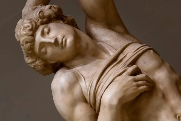 Каменная античная скульптура мужчины, закрывающего глаза.