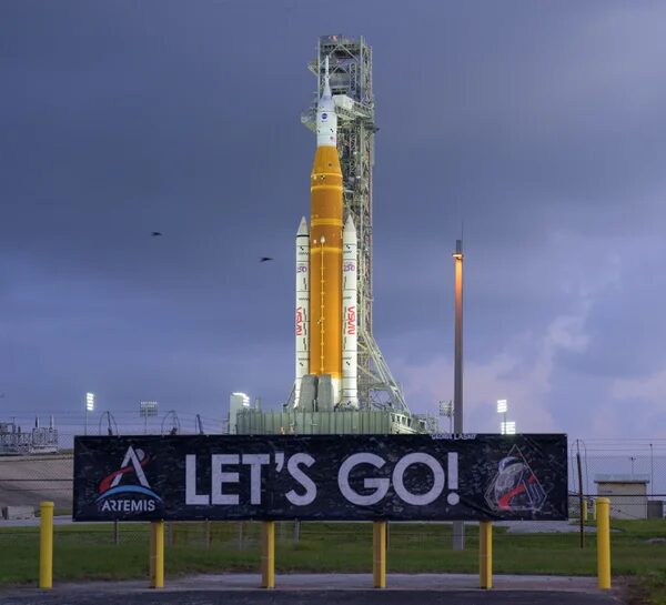 Ракета Artemis SLS готова к запуску на фоне неба с надписью "Let's Go!".