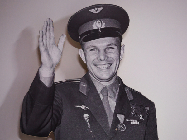 Силуэт военного с поднятой рукой, в форме с медалями и фуражке. Черно-белое фото.