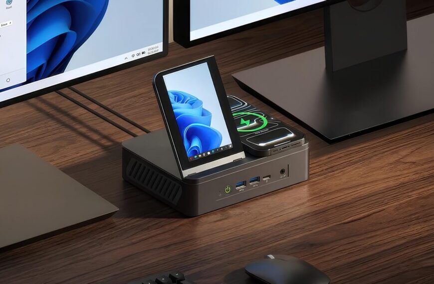 Станция с монитором, смартфоном и зарядкой в интерьере офиса на деревянном столе.