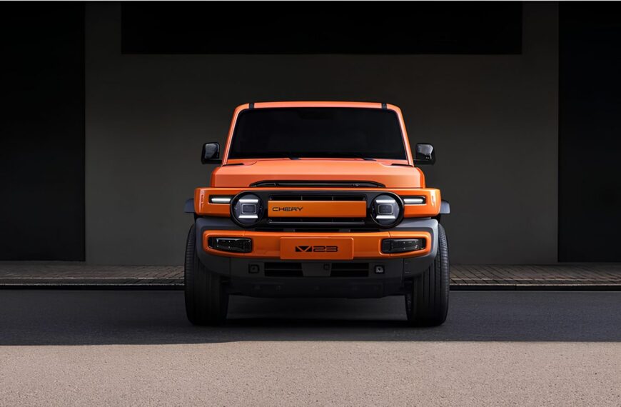 Оранжевый внедорожник Chery X23, вид спереди, на фоне бетонной стены.