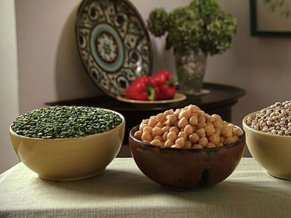 Три миски с горохом на столе, узорчатая тарелка и перцы на заднем плане.
