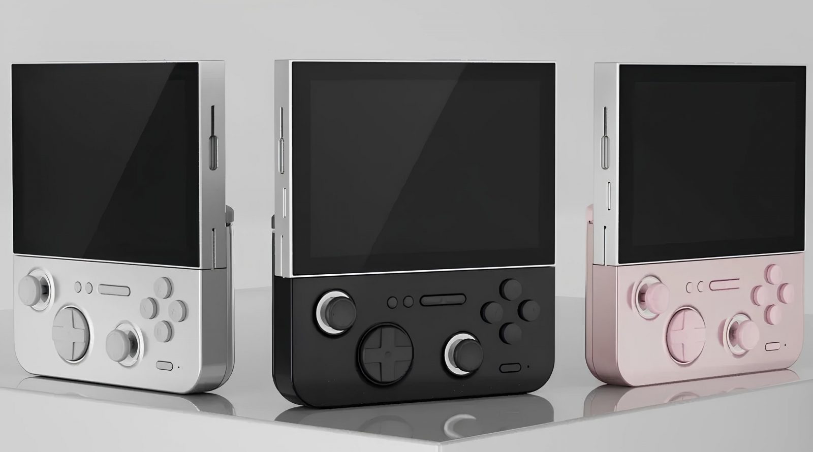 Три портативные игровые приставки разных цветов на светлом фоне.