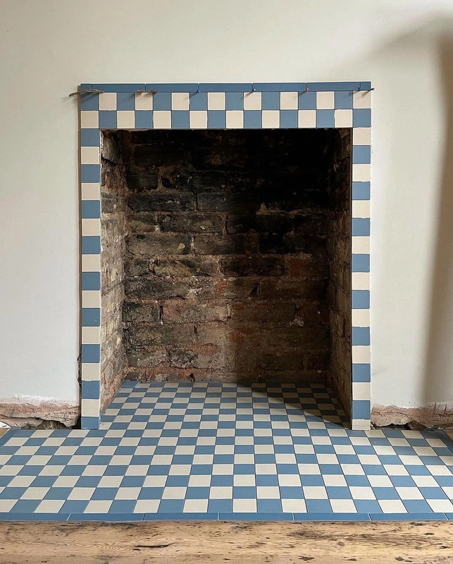 A fireplace with checkerboard tiles from London Mosaic, installed by Heffron Wright Tiling.