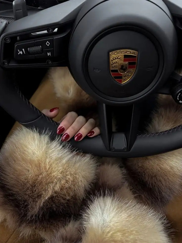 a woman's hand on the steering wheel of a car with fur around it