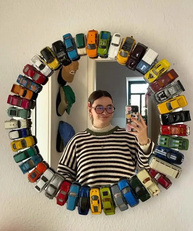 a woman taking a selfie in front of a mirror with cars on the wall