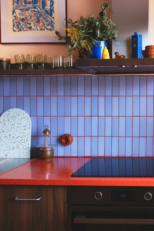 a kitchen with blue and red tiles on the wall, counter top and stovetop