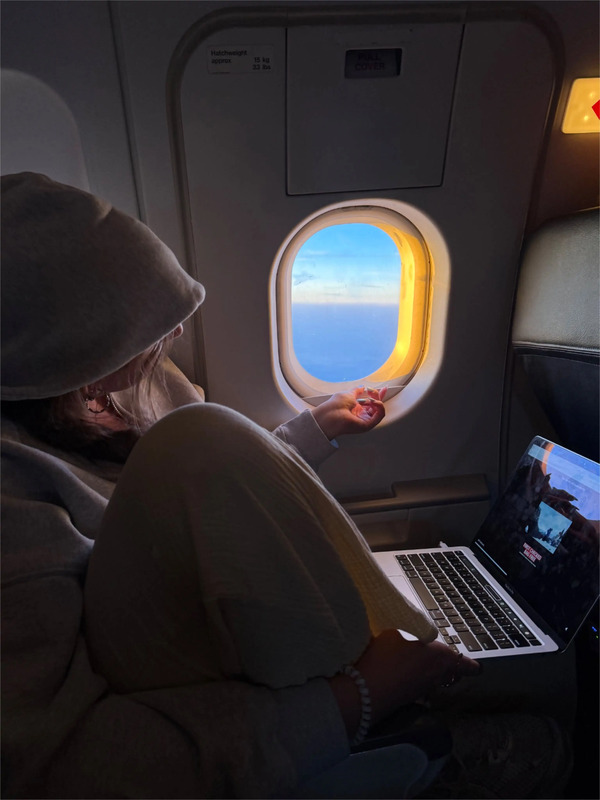 a woman sitting on an airplane looking at her laptop
