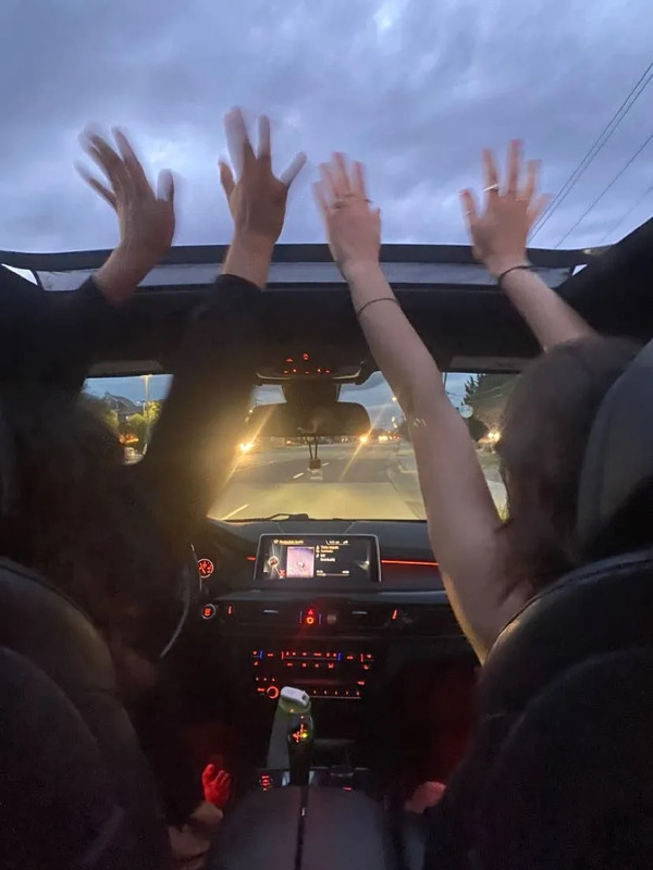 two people sitting in the back seat of a car with their hands up