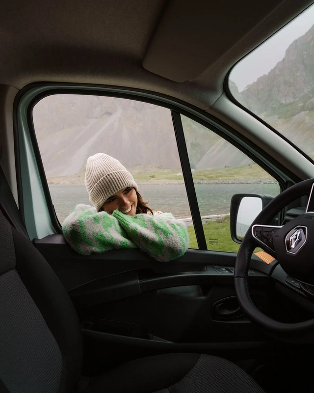 a woman sitting in the passenger seat of a car with her hand on her head