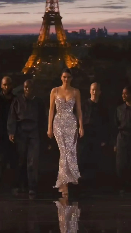 a woman in a silver dress walking down a street next to the eiffel tower