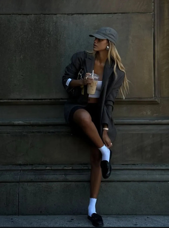 a woman sitting on the side of a building holding a drink