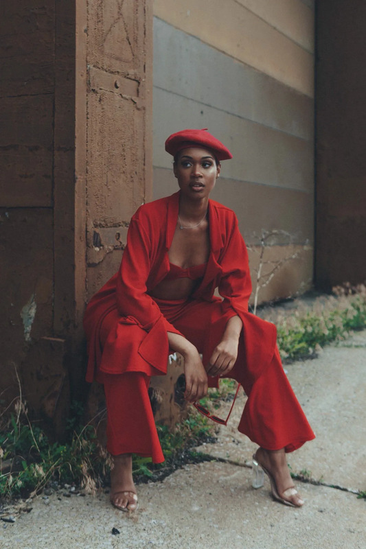 a woman sitting on the ground wearing a red outfit