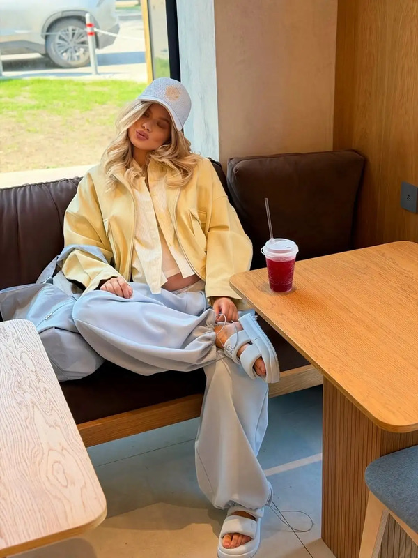 a woman sitting on a bench in front of a table with a cup and drink