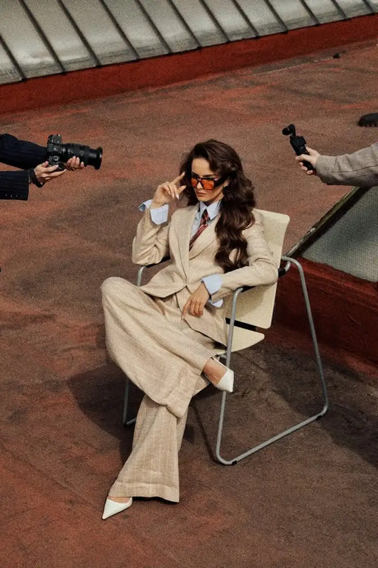 a woman sitting in a chair with two men behind her, one holding a camera